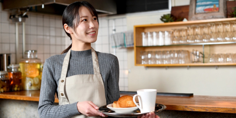 メニューを運んでいる飲食店の女性スタッフ