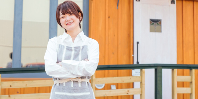 店の前で腕を組んでいる女性の飲食店スタッフ