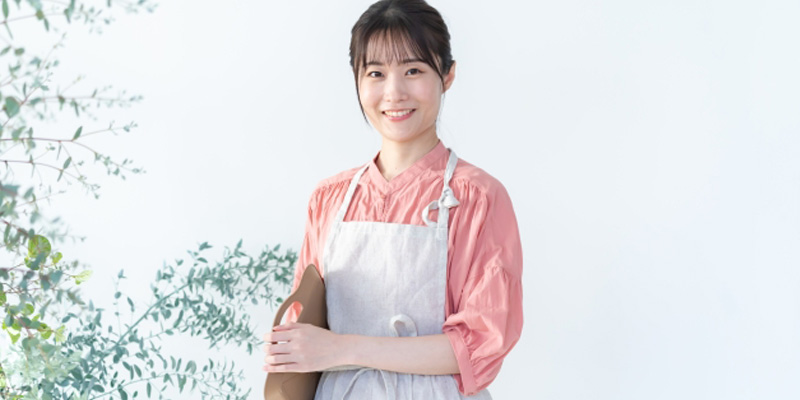 お盆を脇に抱えている笑顔の女性の飲食店スタッフ