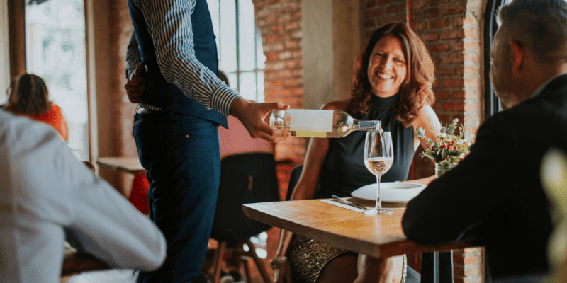 お客さんのグラスにお酒を注ぐ店員