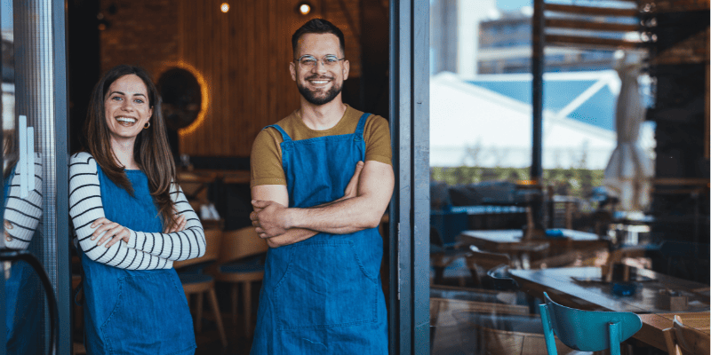 飲食店のスタッフが2人、腕を組んで立っている様子