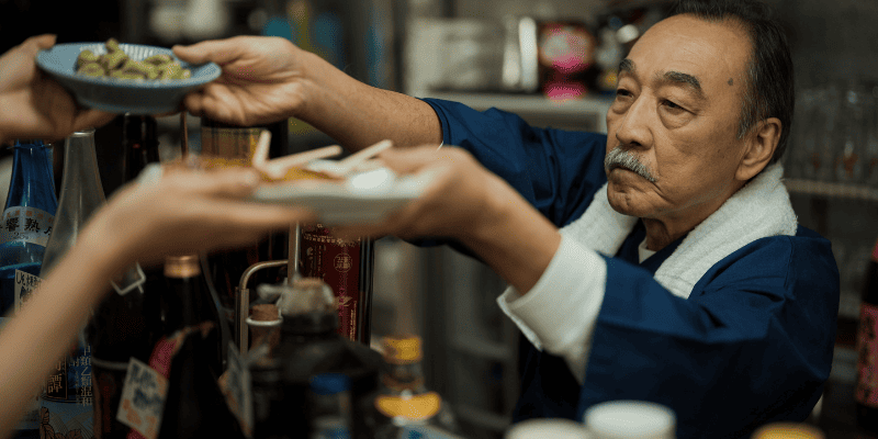 食べ物を渡す居酒屋の店主
