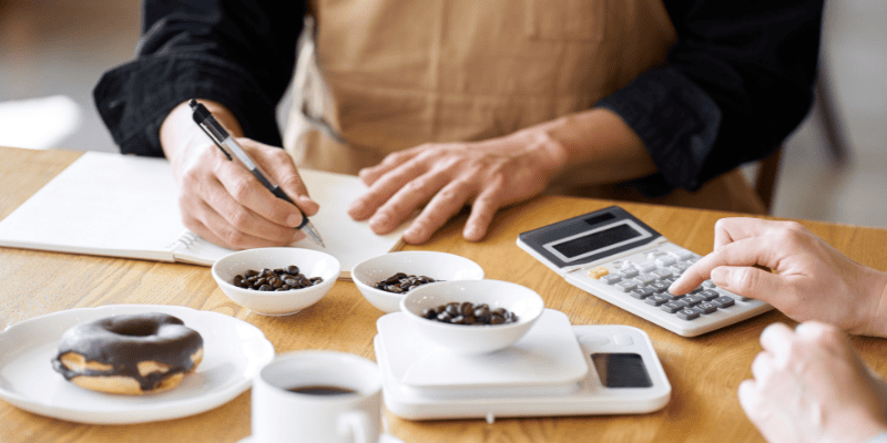 電卓で経費を計算しているコーヒーショップのスタッフ