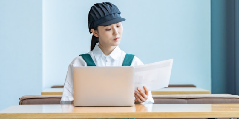 資料を読みながら計算する飲食店女性店員