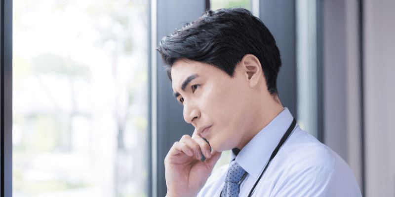 窓を見て考える男性