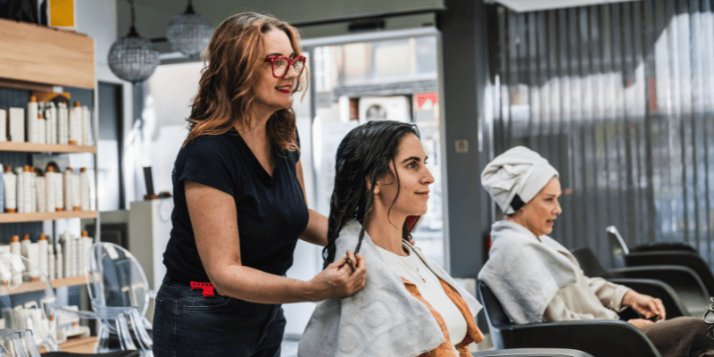 髪の長さを確認する美容師と客