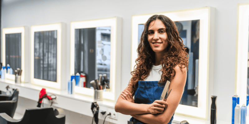 櫛を持って腕を組んでいる美容師