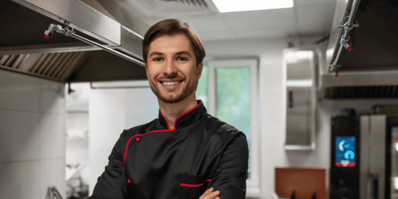 厨房で腕を組んで笑うシェフ