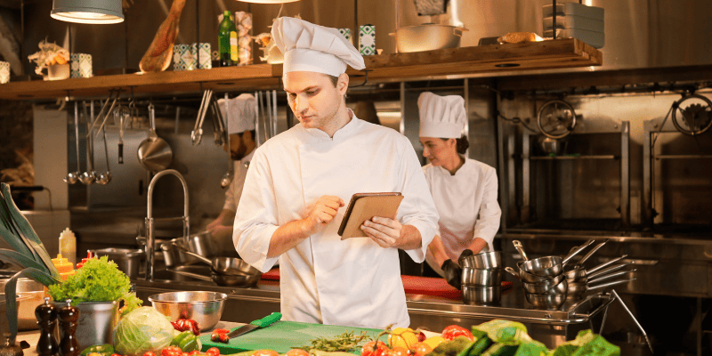 タブレットを操作しながら食材を見るシェフ